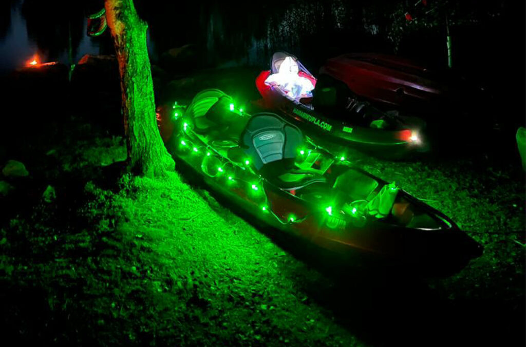 Kuvassa ledivaloin valaistut kanootit loistavat pimeässä rannassa.