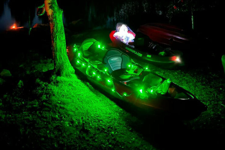 Kuvassa ledivaloin valaistut kanootit loistavat pimeässä rannassa.