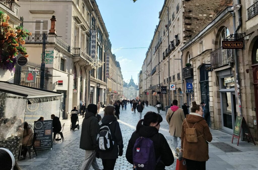 Neljä Jiipin matkalle osallistujaa kävelevät kävelykadulla rankalaisessa Rennesin kaupungissa aurinkoisena päivänä.